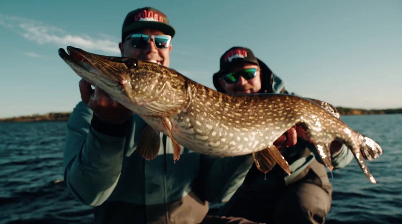 a couple of men holding a fish on a boat