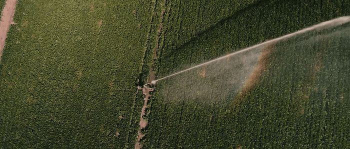 an aerial view of a sprinkler spraying water on a field