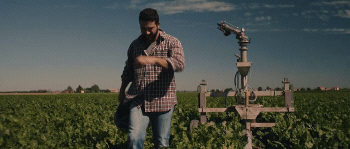 a man standing in a field next to a machine