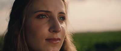 a close up of a woman's face with grass in the background