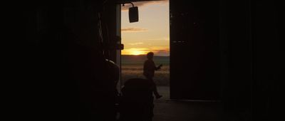 a silhouette of a person walking out of a door