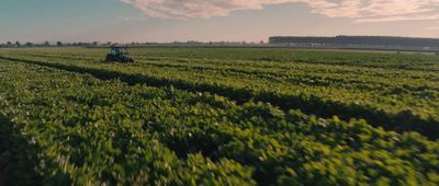 a tractor is driving through a large green field