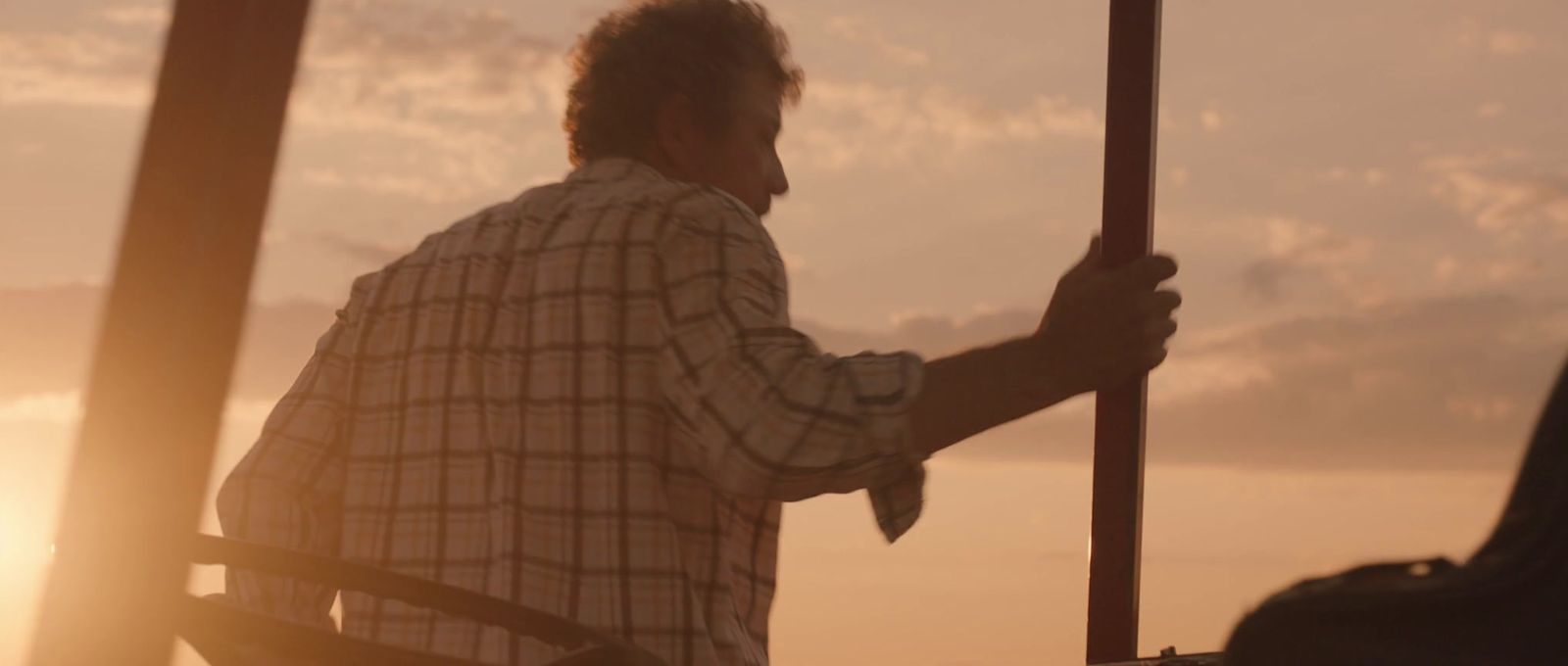 a man holding a pole in front of a sunset