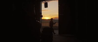 a silhouette of a person walking out of a door