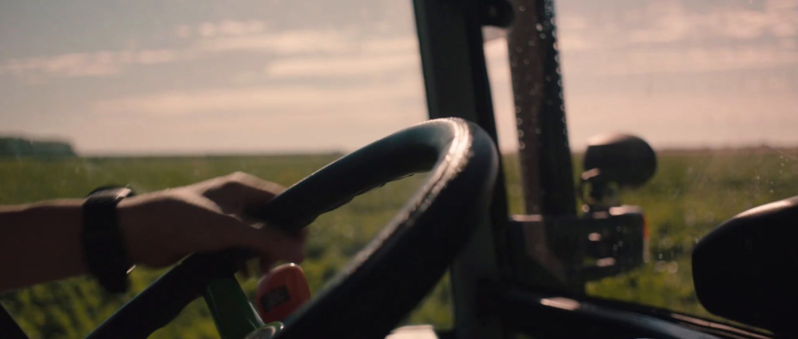 a person driving a bus through a lush green field