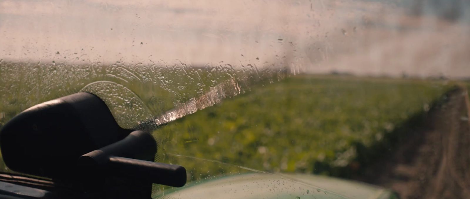 a view of a field through a rain covered window