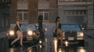 a group of women walking down a street next to parked cars