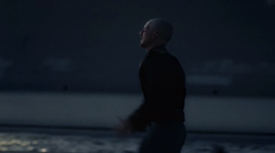 a man in a black jacket is walking by the water