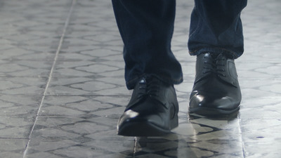 a close up of a person's shoes on a tiled floor