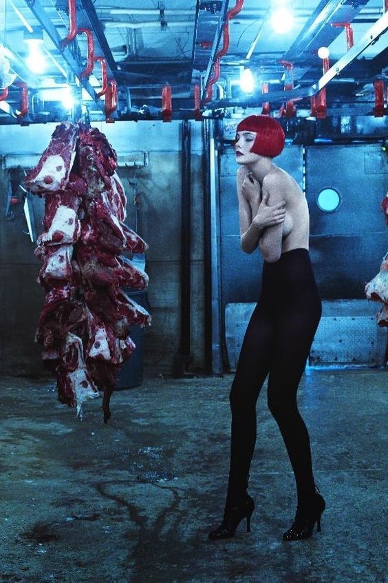 a woman in tights and heels standing next to a pile of dead meat