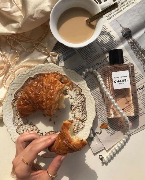 a person holding a pastry on a plate next to a cup of coffee