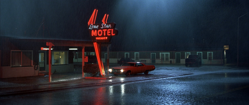 a red car is parked in front of a motel