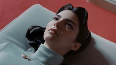 a woman laying on top of a couch next to a cat