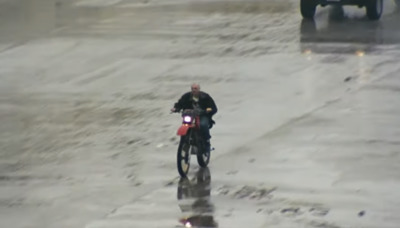 a man riding a motorcycle on a wet street