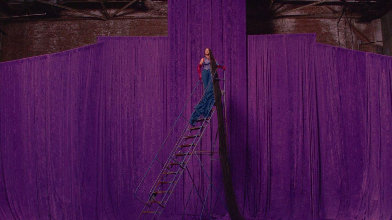 a woman standing on top of a purple curtain