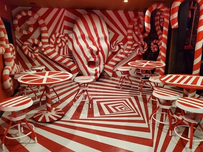 a red and white striped room with stools and tables