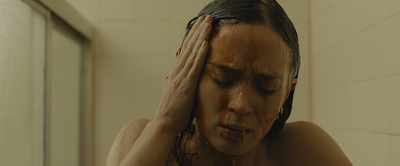 a woman in a shower holding her head with her hands