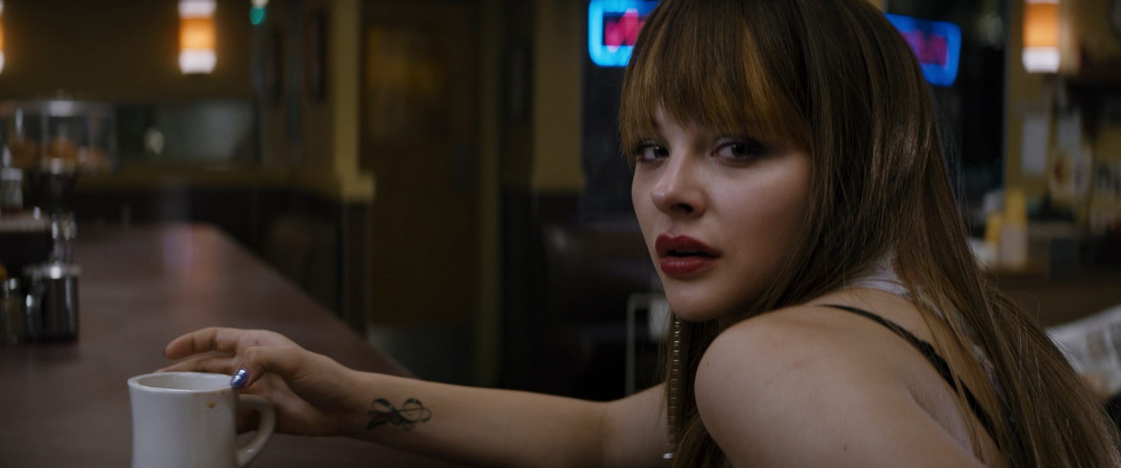 a woman sitting at a bar with a cup of coffee