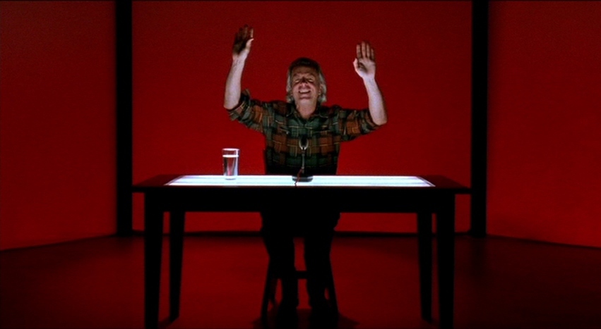 a man sitting at a table with his arms in the air