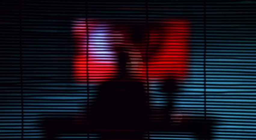 a person standing in front of a window with blinds