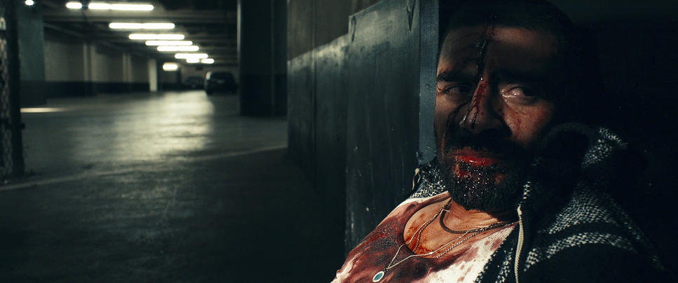 a man with blood on his face standing next to a wall