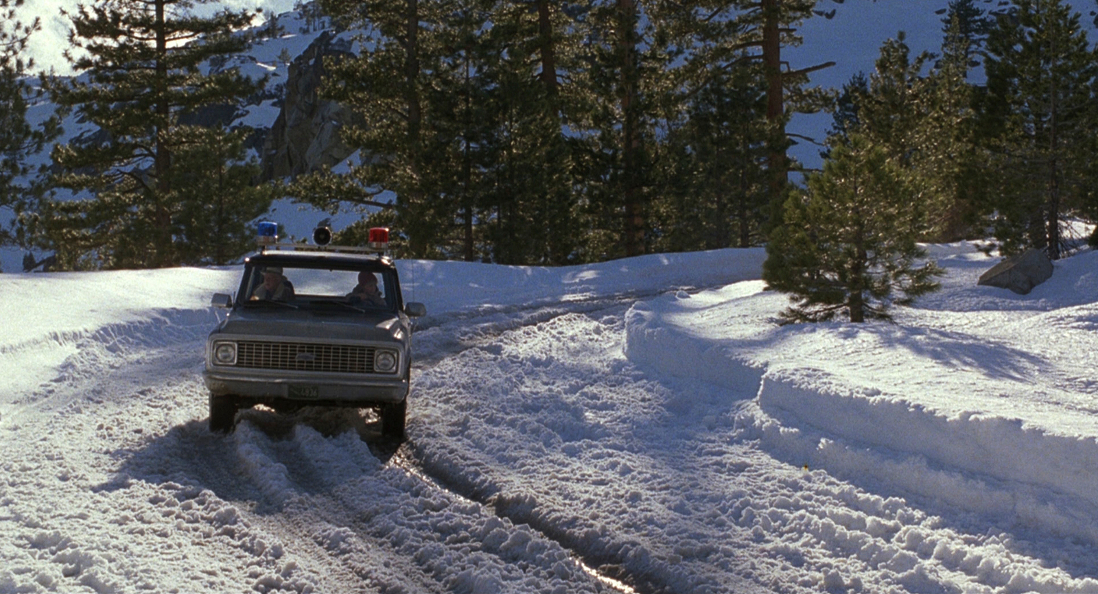 a truck driving down a snow covered road