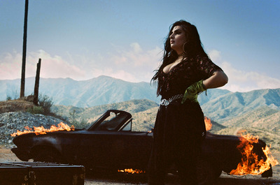 a woman standing next to a car on a road