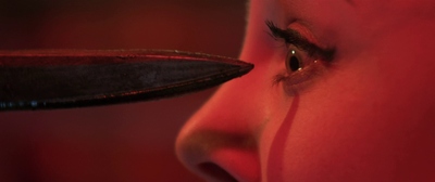 a close up of a woman's eye with a knife in front of her