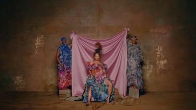 a group of women standing next to each other in front of a pink curtain