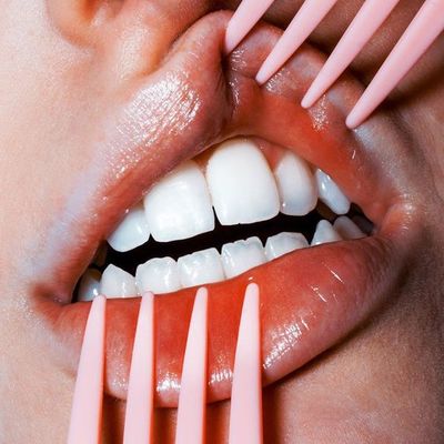 a close up of a person holding a toothbrush to their mouth