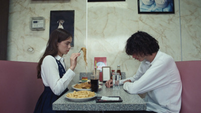 a man and woman sitting at a table eating pasta