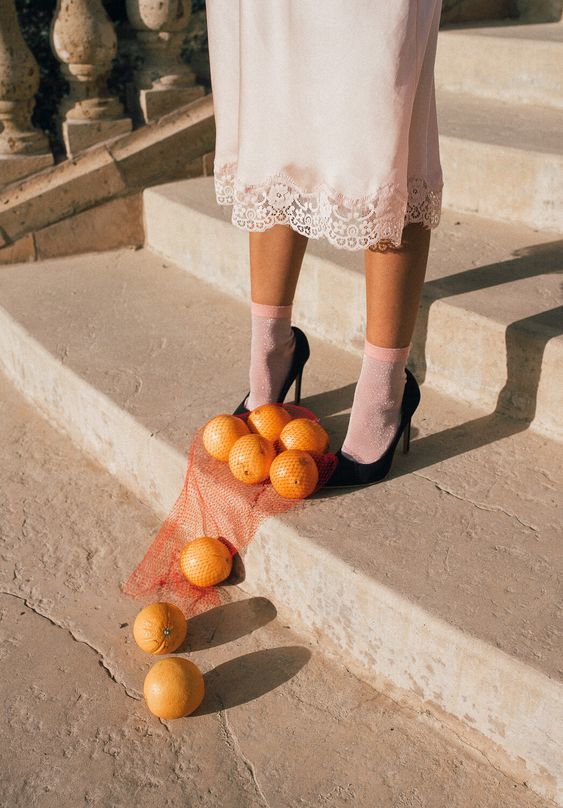 a woman standing on a set of stairs with oranges