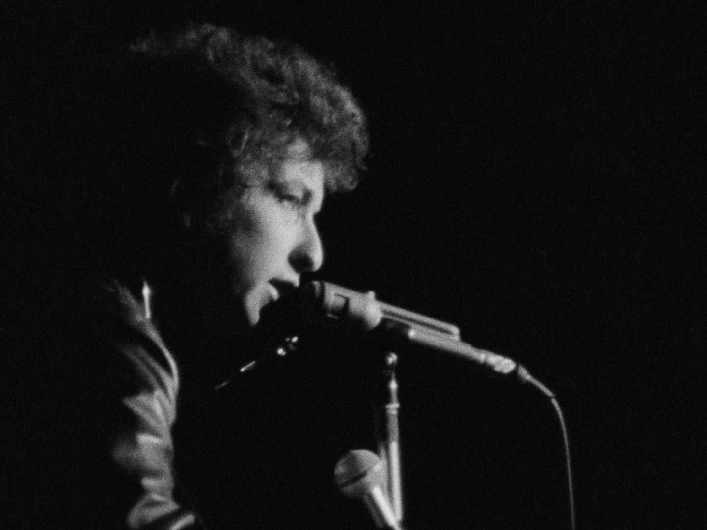 a black and white photo of a man singing into a microphone