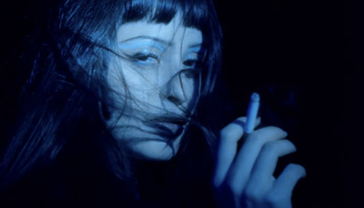 a woman is smoking a cigarette in the dark