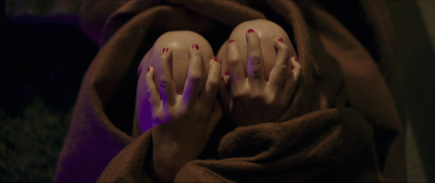 a person with long nails and red nails laying on a blanket