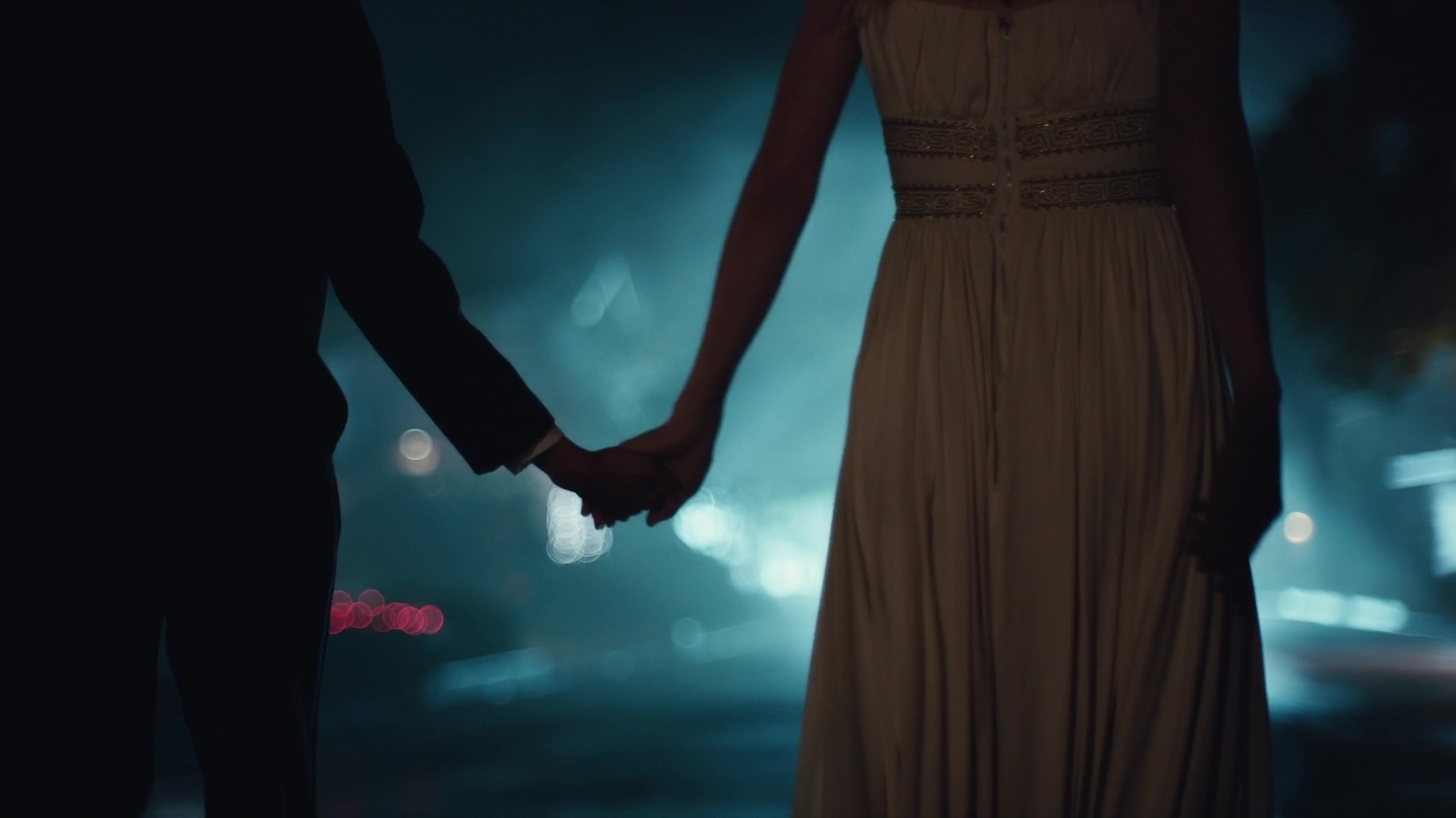 a man and a woman holding hands in the dark