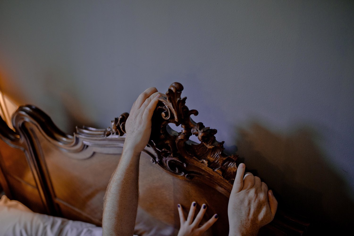 a person reaching up to a bed with a wooden headboard