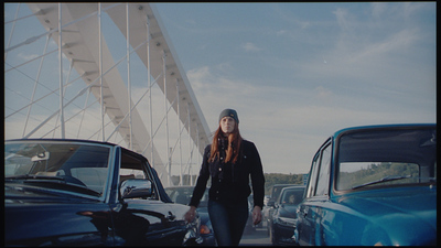 a woman walking through a parking lot next to parked cars