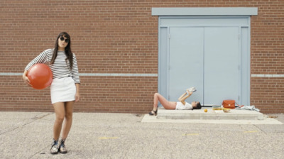 a woman holding a basketball standing next to a woman laying on the ground