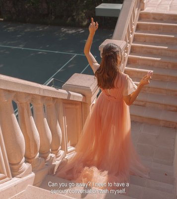 a little girl in a pink dress standing on a balcony