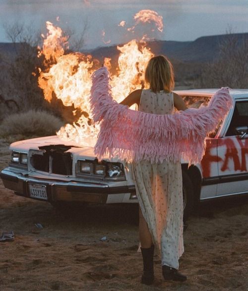 a woman standing next to a car on a field