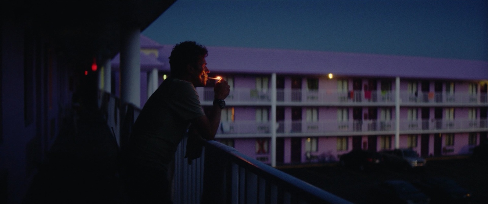 a man standing on a balcony smoking a cigarette