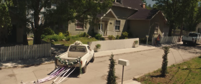 a small truck with a bunch of flowers on it is parked in front of a house