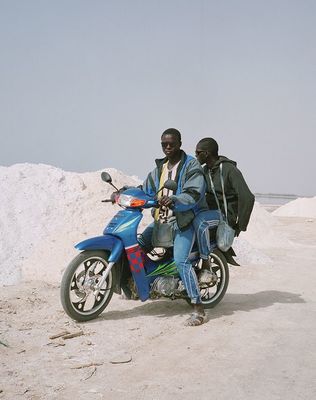 two men sitting on a motorcycle in the desert