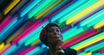 a woman with headphones is standing in front of colorful lights