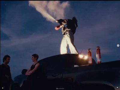 a man standing on top of a car holding a baseball bat