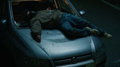 a man laying on the hood of a car