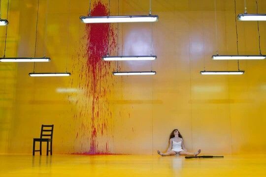 a woman sitting on the floor in front of a yellow wall