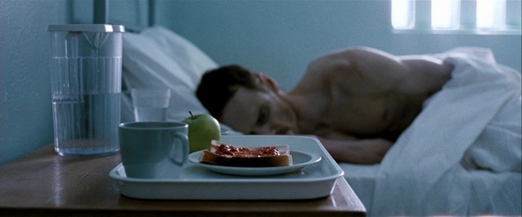 a man laying in bed with a plate of food on a tray