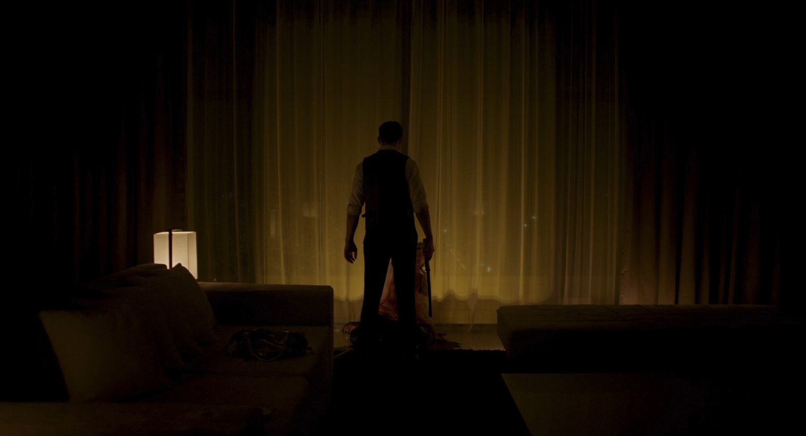 a man standing in a dark room next to a couch